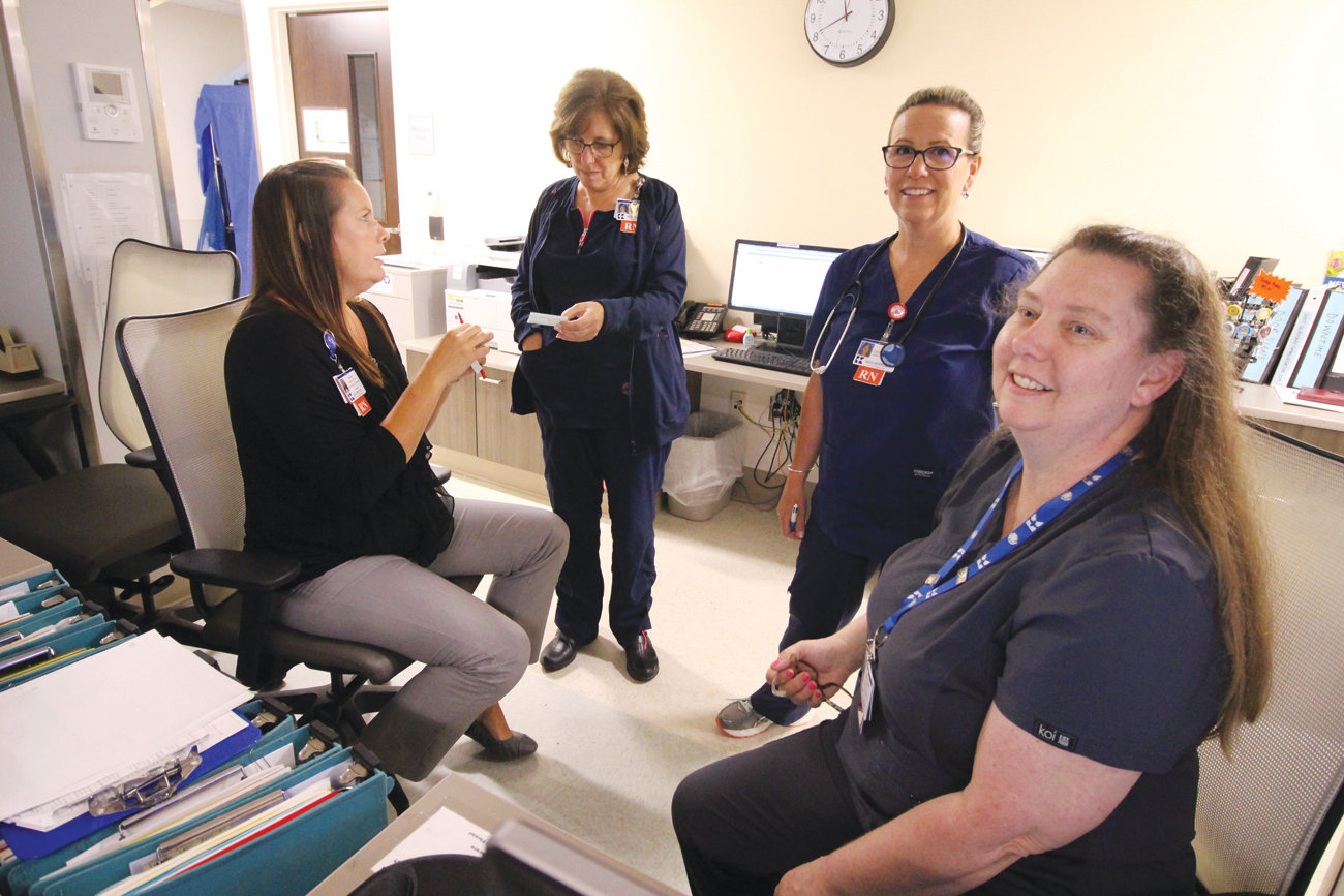 TEAM EFFORT: Karen Wholey, who heads up training for relationship-based care, goes over plans with nurses Celeste Smith and Linda St. Jean and secretary Mary Ann Hutchins at the 2-North nursing station.